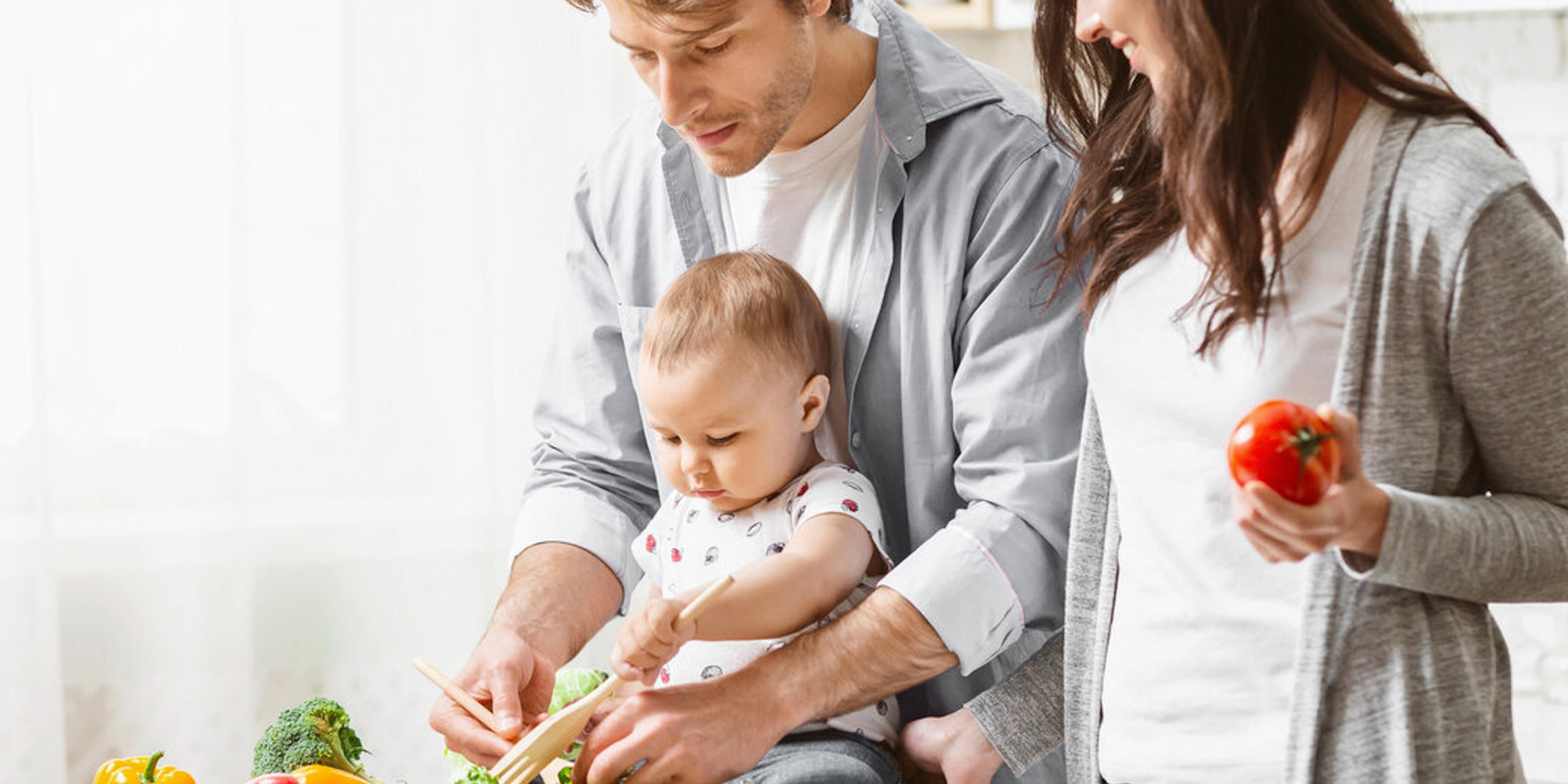 Eltern rüsten Gemüse mit Baby am Tisch – Familienzeit-Initiative für 18 Wochen gemeinsame Zeit